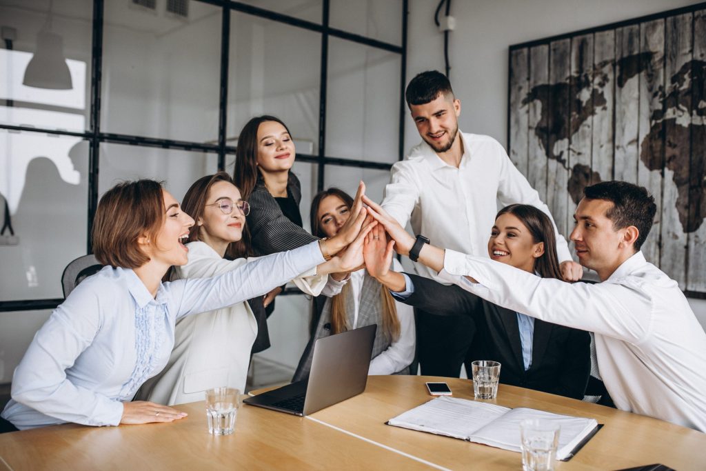 Grupo de profesionales de Proconsi uniendo sus manos en la oficina durante una reunión de equipo