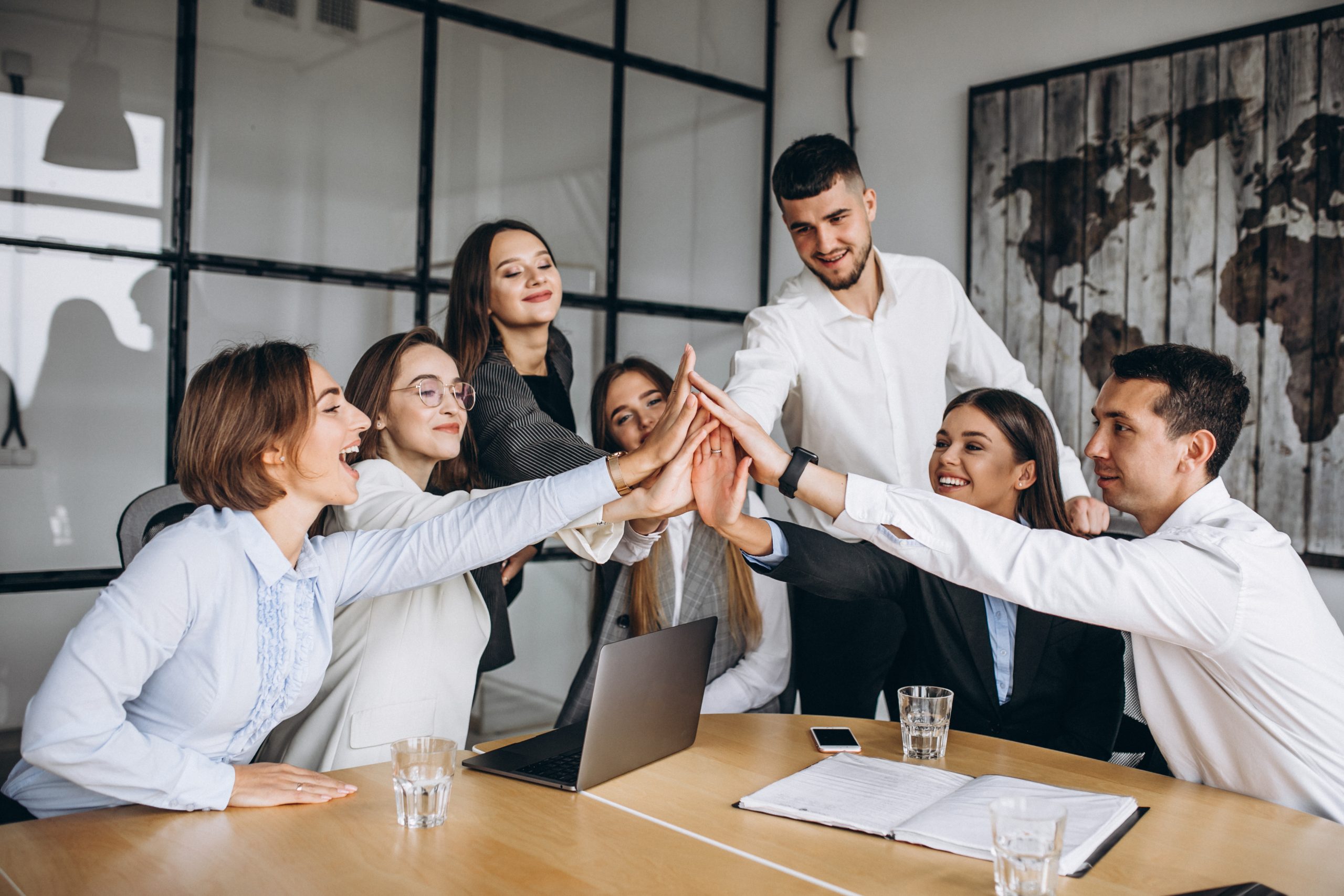 Grupo de profesionales de Proconsi uniendo sus manos en la oficina durante una reunión de equipo