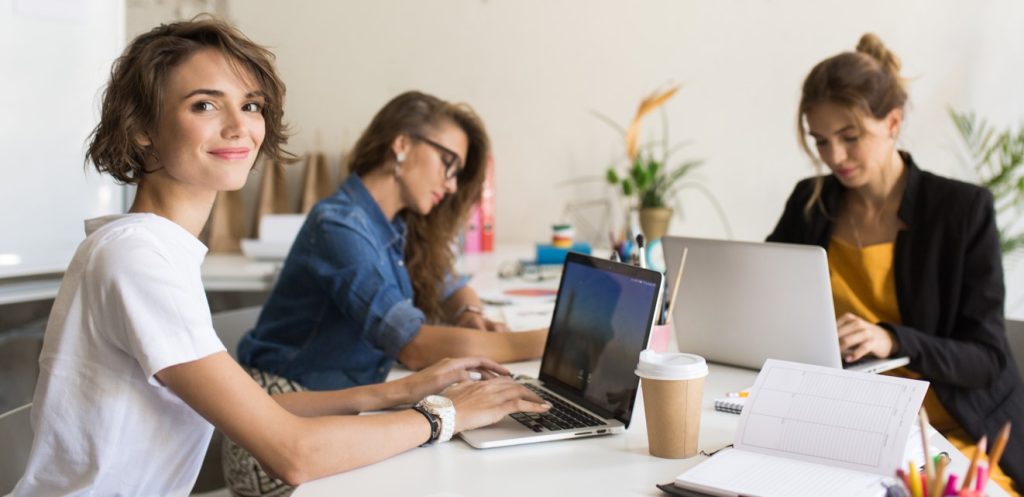 Mujeres profesionales colaborando con sus ordenadores portátiles en una oficina tecnológica